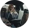 Businesswoman working on a laptop and talking on the phone in the backseat of a car