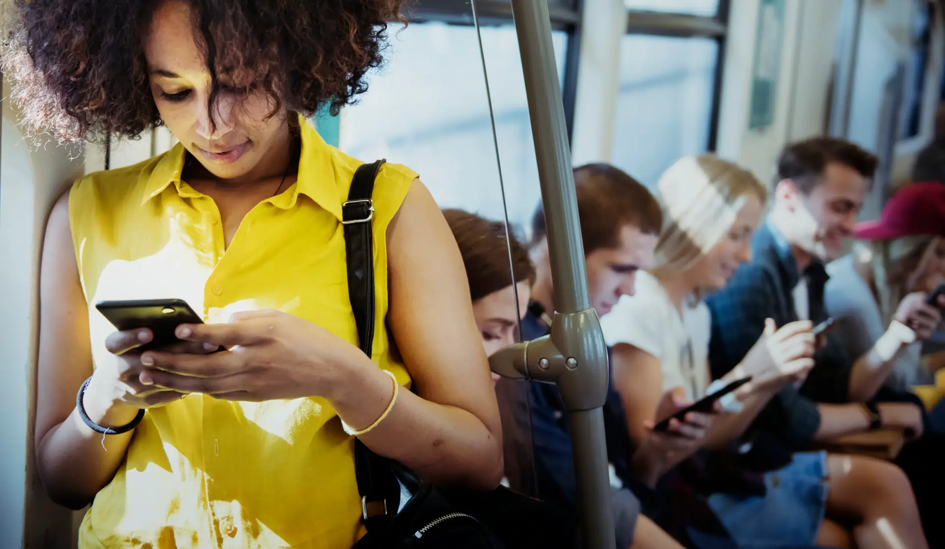 Young woman wearing yellow sleeveless using a smartphone in a subway