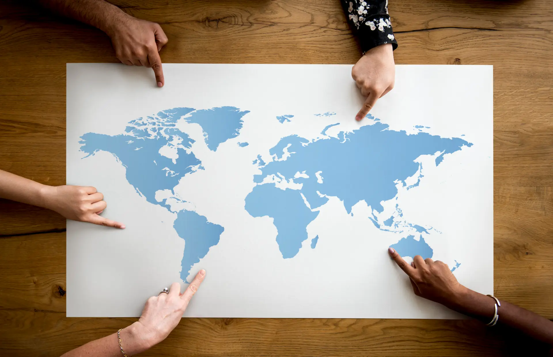 a group of people pointing on the world map for international clients